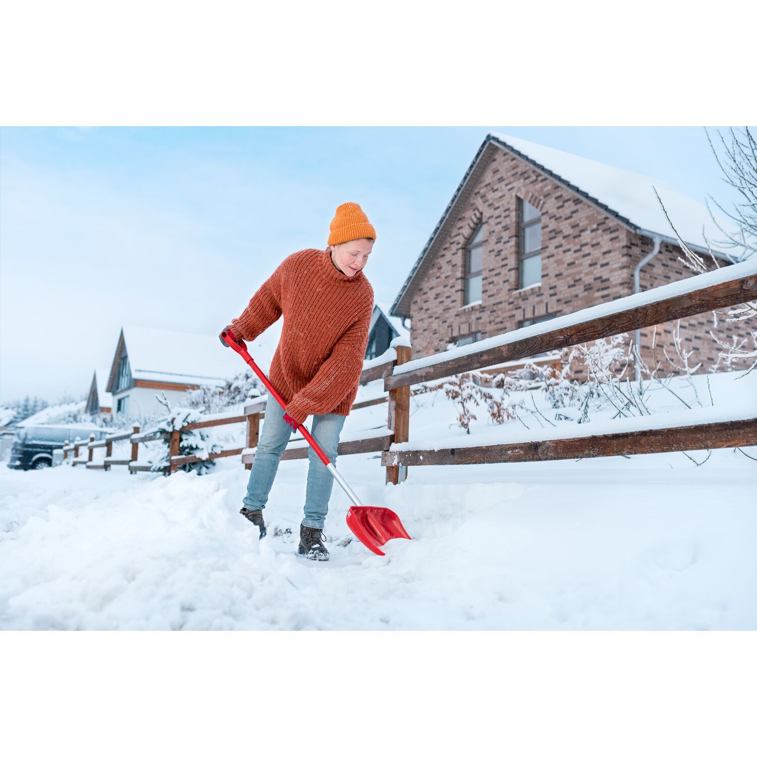 A woman clears a snow-covered sidewalk with the SN-M 42 / ZM-AD 120 snow shovel from WOLF-Garten